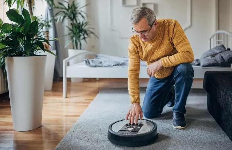 Uomo con robot aspirapolvere